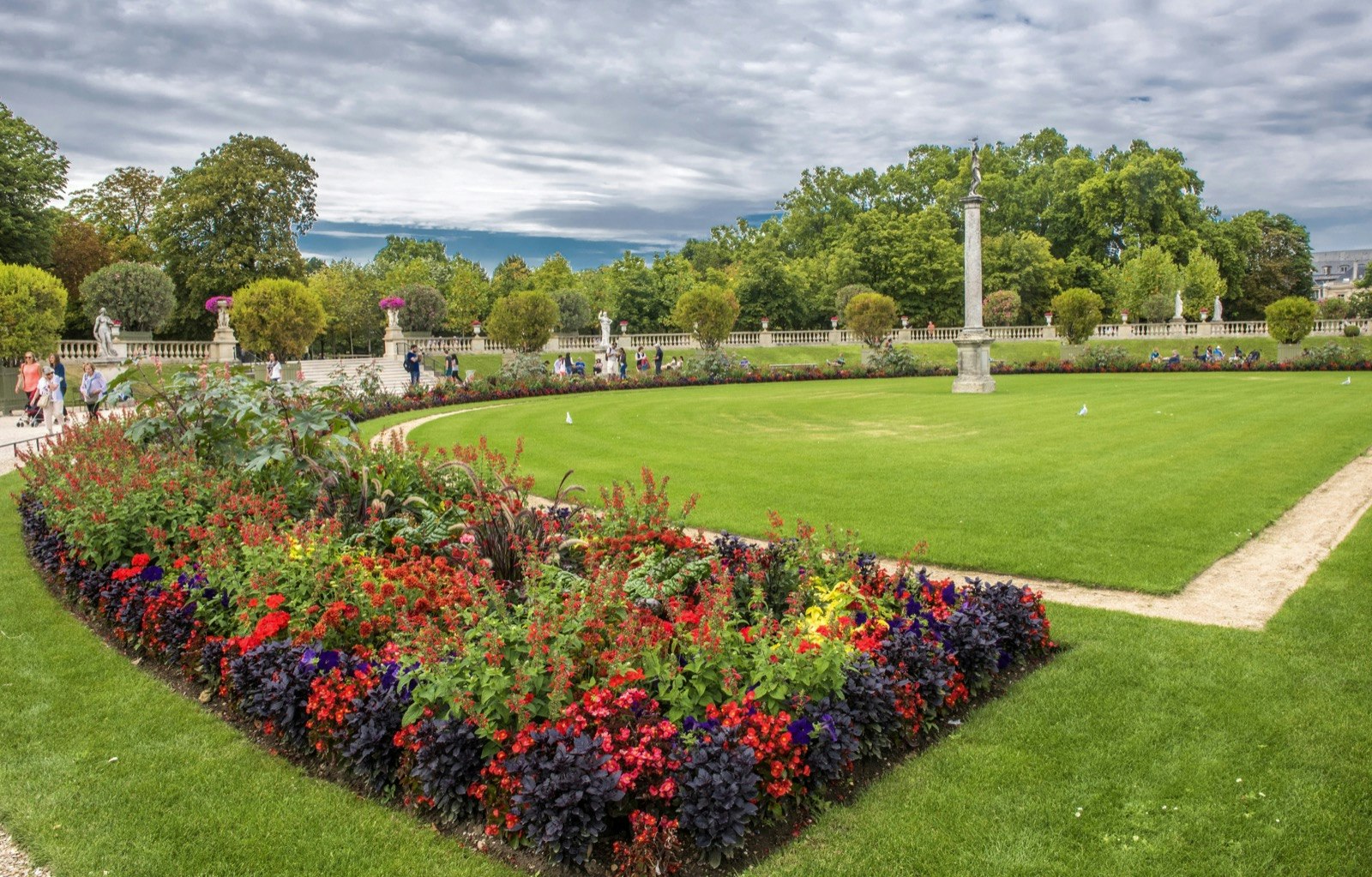 Flowers bloom around a green lawn at the Jardin du Luxembourg